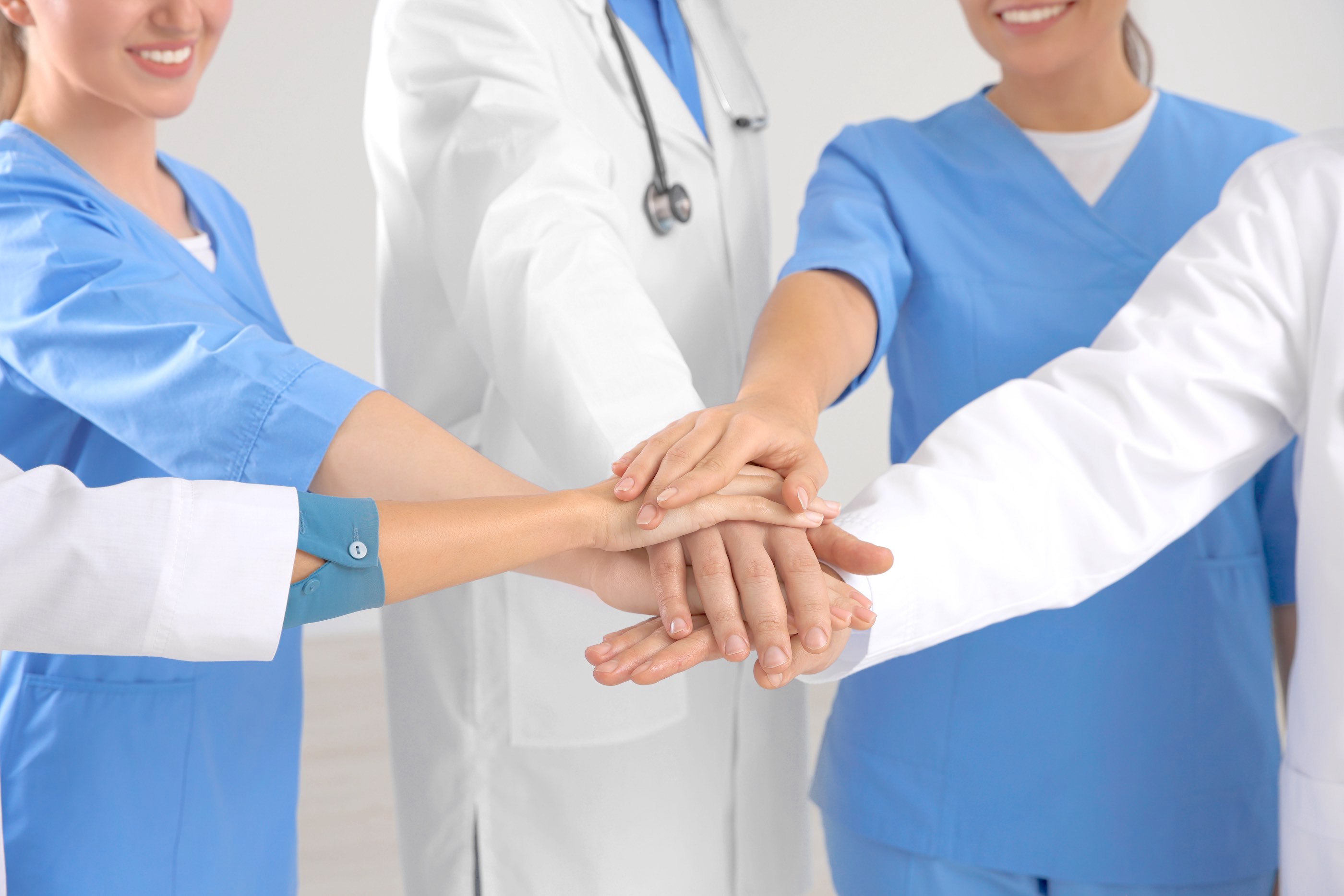 Team of medical doctors putting hands together indoors, closeup